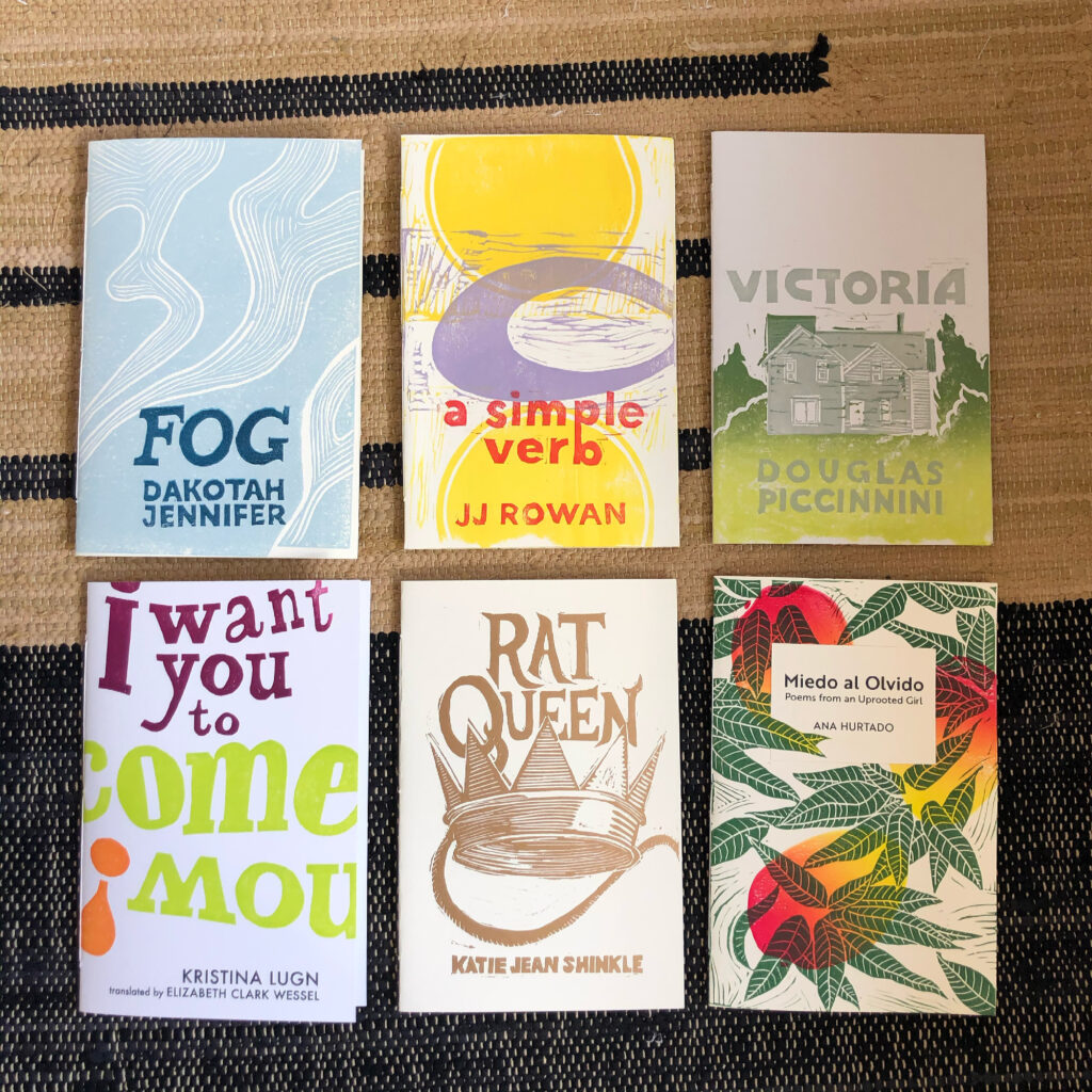 All six chapbooks, arranged in a three-by-three grid on a woven rug. The covers are colorfully printed by hand from hand-carved linocut blocks.